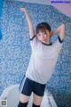 A woman in a white shirt and blue shorts posing in a bathtub.