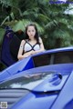 A woman sitting on top of a blue sports car.