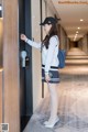 A woman in a school uniform leaning against a door.