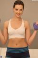 A woman in a white bra top and blue shorts holding two purple dumbbells.