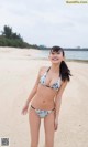 A woman in a bikini standing on a beach.