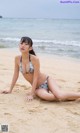 A woman in a bikini sitting on the beach.