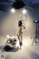 A naked woman standing next to a stuffed animal.