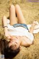 A woman laying on top of a pile of hay.