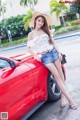 A woman in a straw hat leaning on a red car.