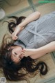 A woman laying on the floor with her hair blowing in the wind.