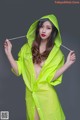 A woman in a bright green raincoat holding a stick.