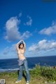 A naked woman standing on top of a grass covered hill.