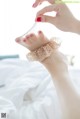 A woman's hand holding a pair of barefoot sandals on a bed.