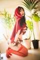 A woman in a red hooded outfit sitting on a table.