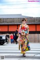 A woman in a colorful kimono crossing the street.