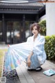 A woman in a blue kimono holding an umbrella.