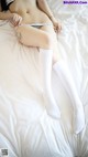 A woman laying on top of a bed wearing white stockings.