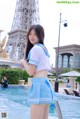 A woman in a blue and white uniform standing next to a pool.