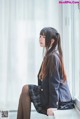 A woman in a school uniform sitting on a window sill.