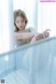 A woman sitting on a bed looking out a window.