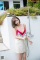 A woman in a red and white dress holding a shower head.