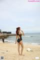 A woman in a black bathing suit standing on a beach.