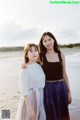 Two young women standing next to each other on a beach.