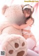 A woman is hugging a large teddy bear on a bed.