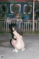 A woman in a white thong crouching down in front of a carousel.