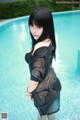 A woman in a black dress standing in a pool.