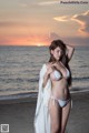 A woman in a white bikini standing on a beach.