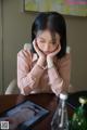 A woman sitting at a table with her head in her hands.